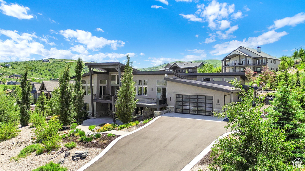 Modern home with stone siding, asphalt driveway, a garage, and a residential view