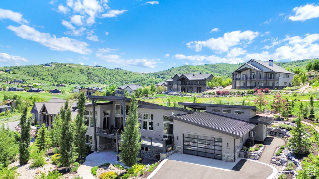 View of front facade with a mountain view, stone siding, a residential view, and asphalt driveway