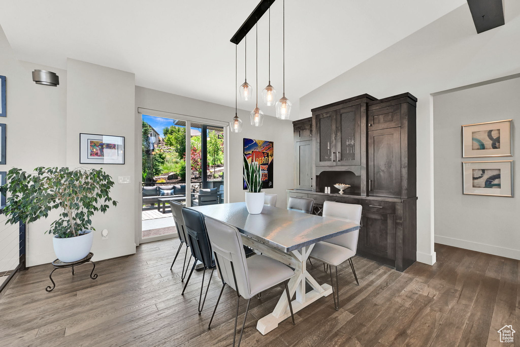 Dining space featuring wood finished floors, lofted ceiling, and baseboards