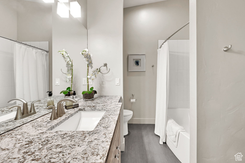 Bathroom with vanity, toilet, tile patterned floors, shower / bath combo, and baseboards