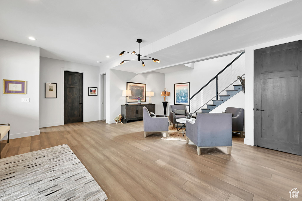 Living room featuring wood finished floors, stairs, recessed lighting, a chandelier, and baseboards