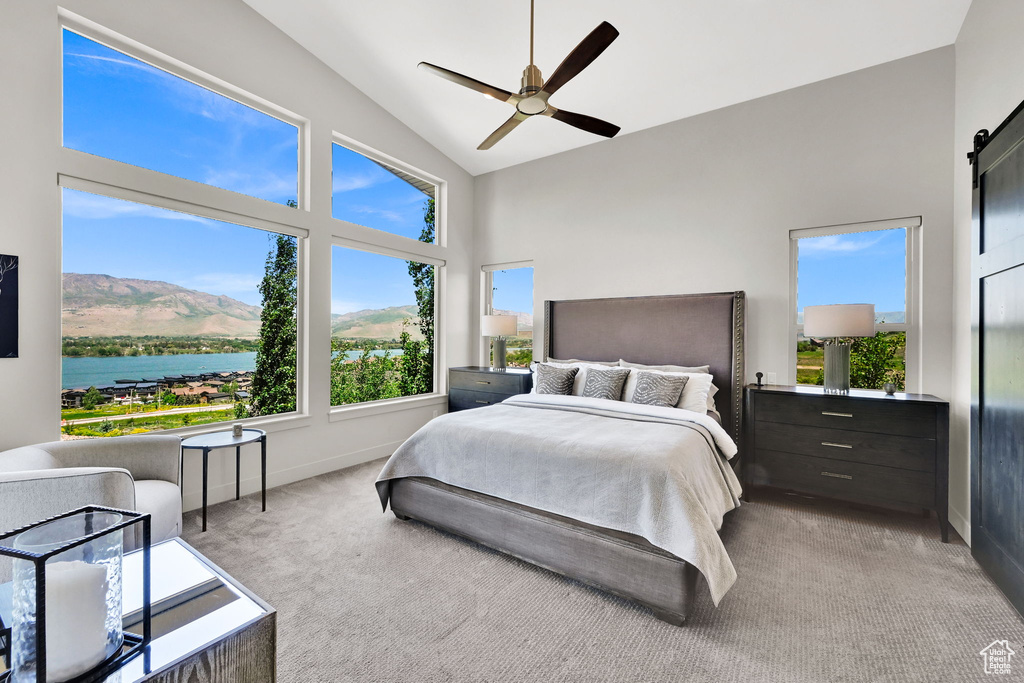 Bedroom with carpet flooring, baseboards, high vaulted ceiling, a barn door, and ceiling fan
