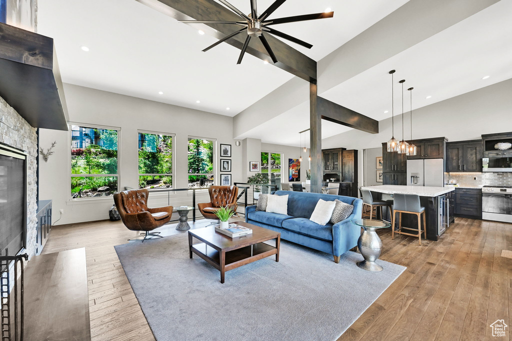 Living area with recessed lighting, light wood finished floors, high vaulted ceiling, a chandelier, and a glass covered fireplace