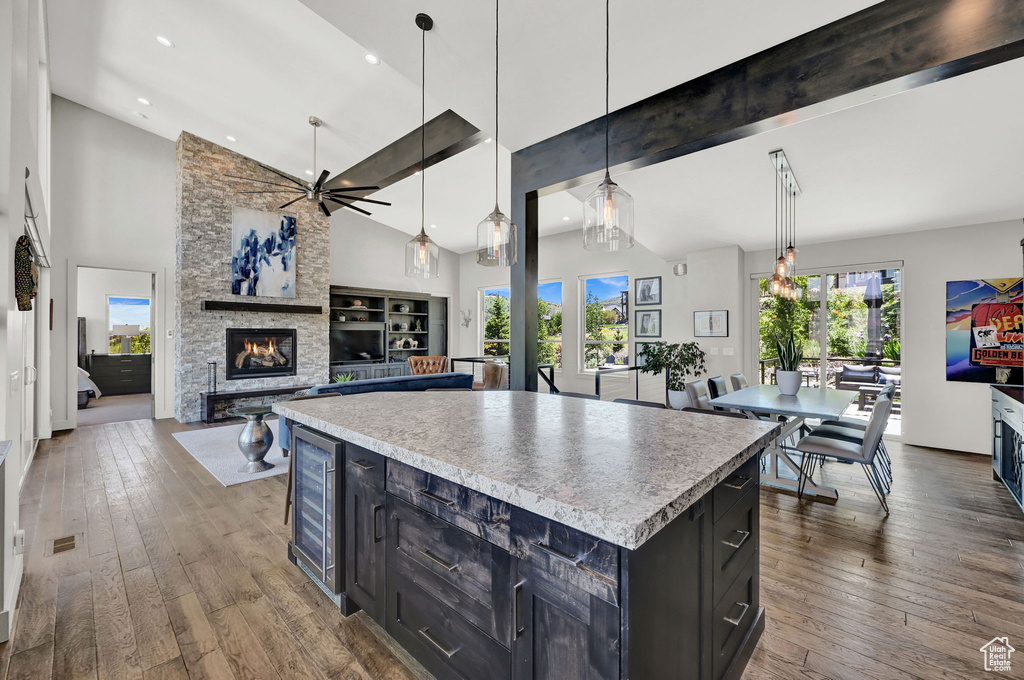 Kitchen featuring a fireplace, a ceiling fan, beverage cooler, dark cabinets, and hardwood / wood-style floors