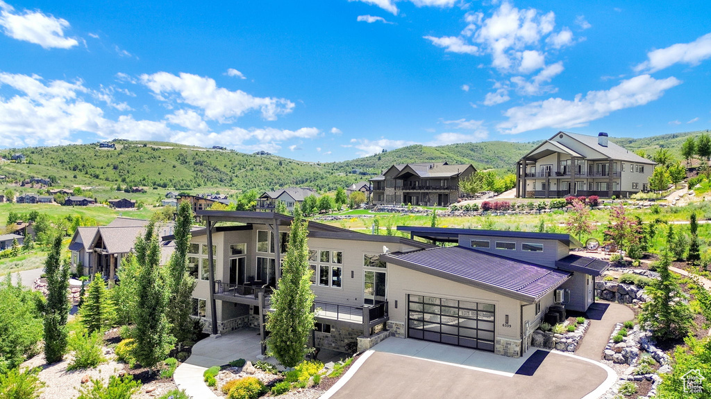 View of front facade featuring stone siding, a mountain view, a residential view, asphalt driveway, and a garage