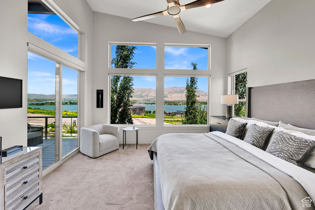 Carpeted bedroom featuring access to exterior, high vaulted ceiling, a water and mountain view, and ceiling fan