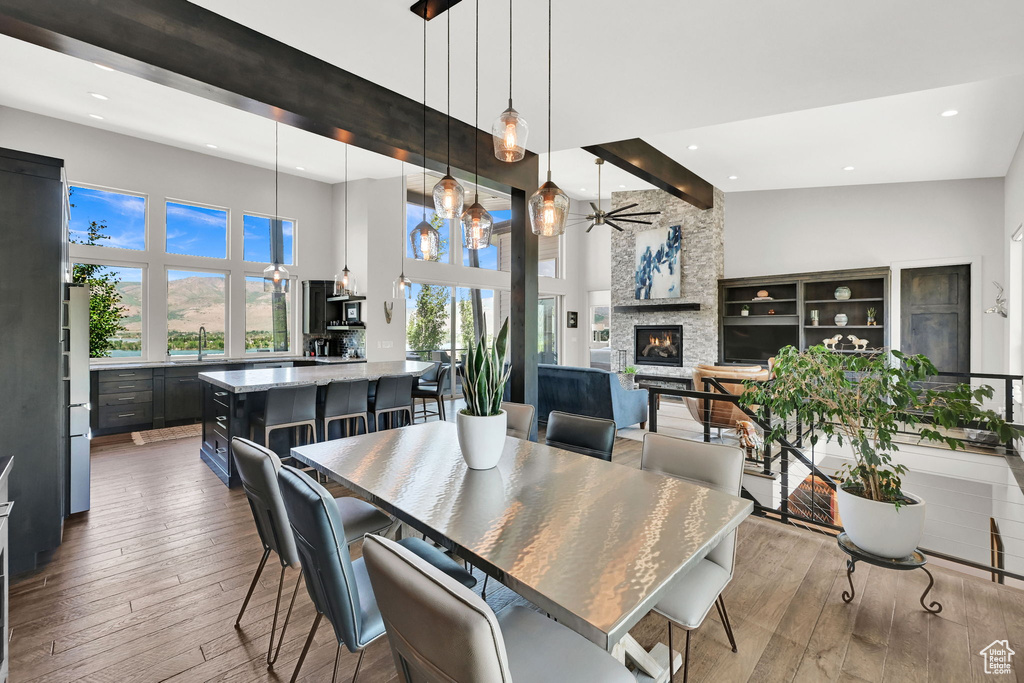 Dining area featuring a towering ceiling, recessed lighting, a ceiling fan, wood-type flooring, and a fireplace