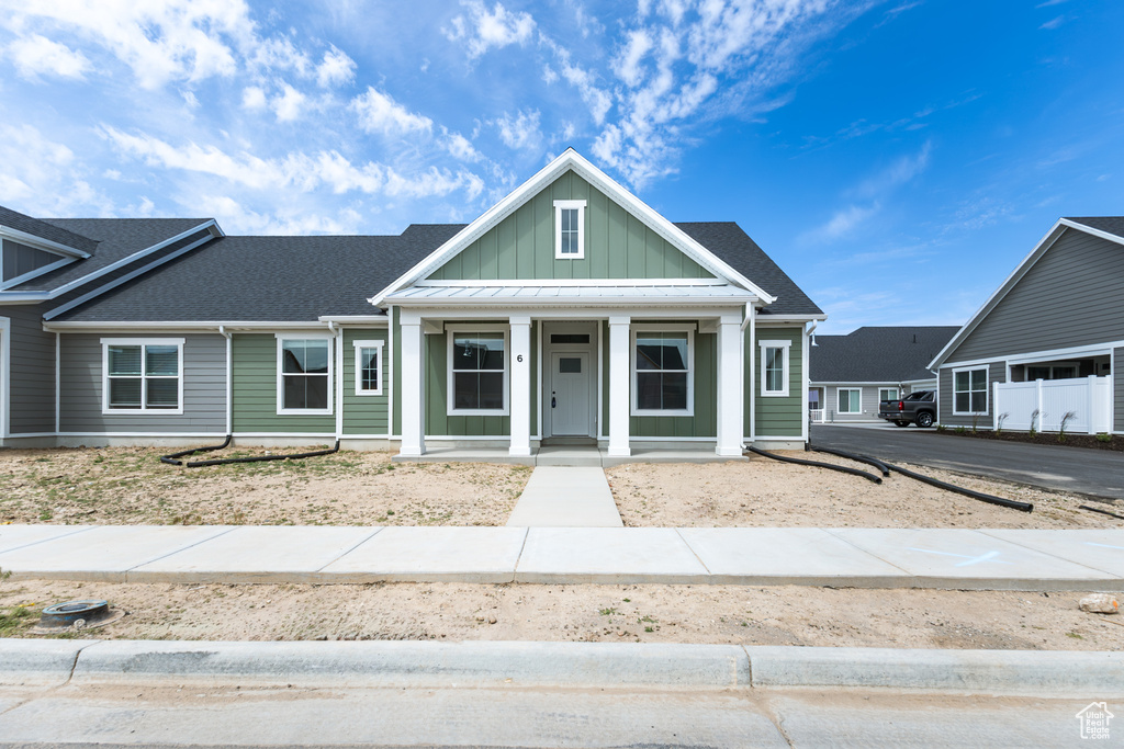 View of front of property with covered porch, board and batten siding, and roof with shingles