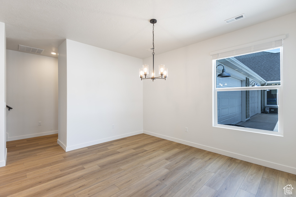 Spare room featuring wood finished floors, baseboards, and a chandelier