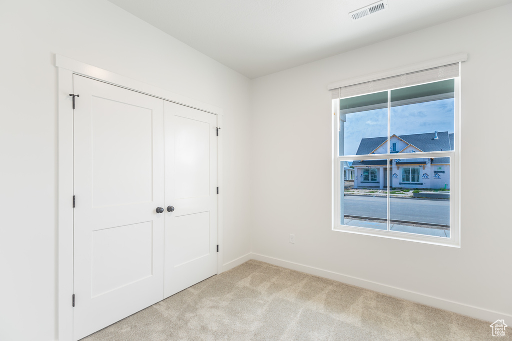 Unfurnished bedroom with light colored carpet, a closet, and baseboards