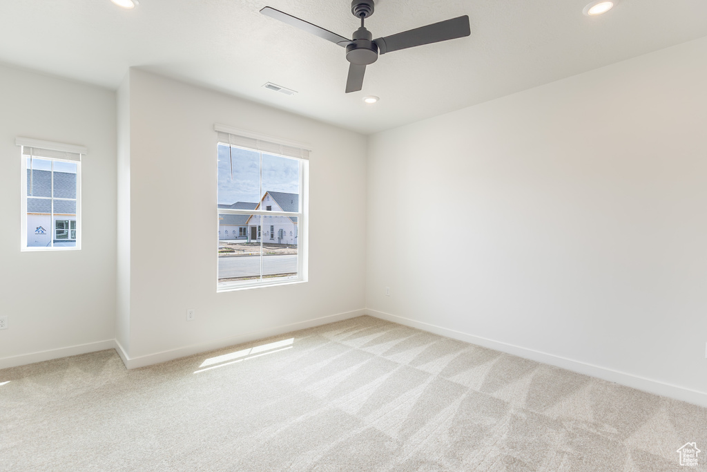 Unfurnished room with light carpet, healthy amount of natural light, ceiling fan, and recessed lighting
