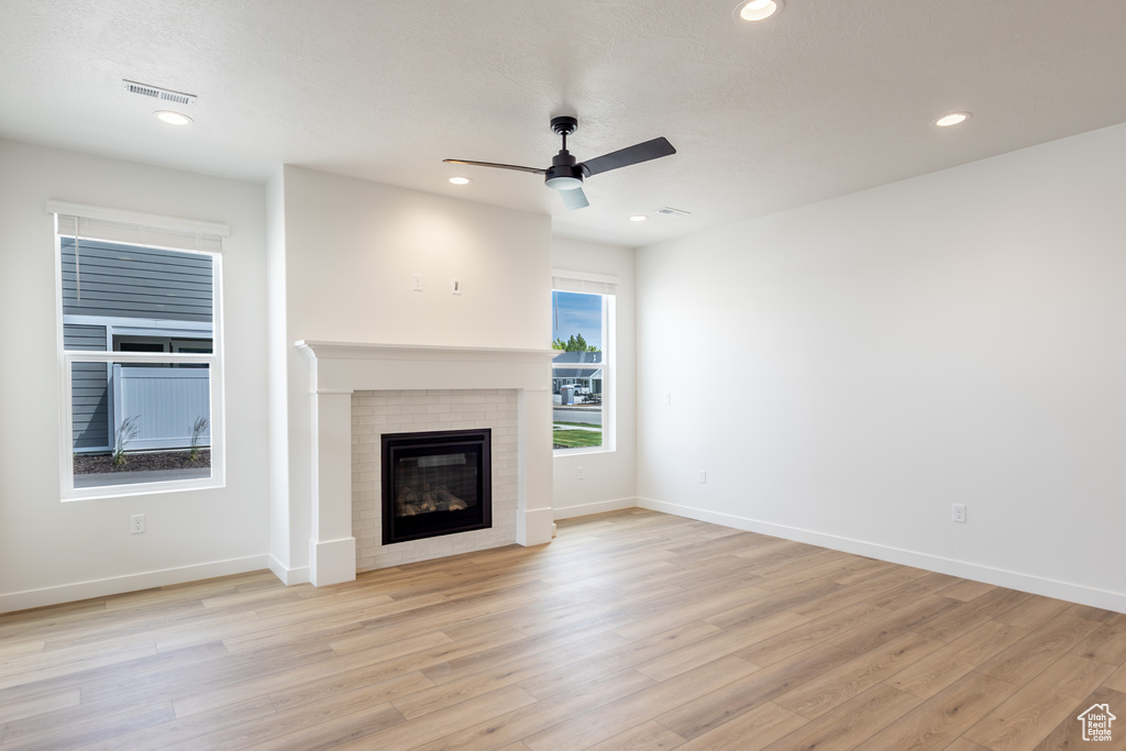 Unfurnished living room featuring ceiling fan, a brick fireplace, light wood-style flooring, recessed lighting, and baseboards
