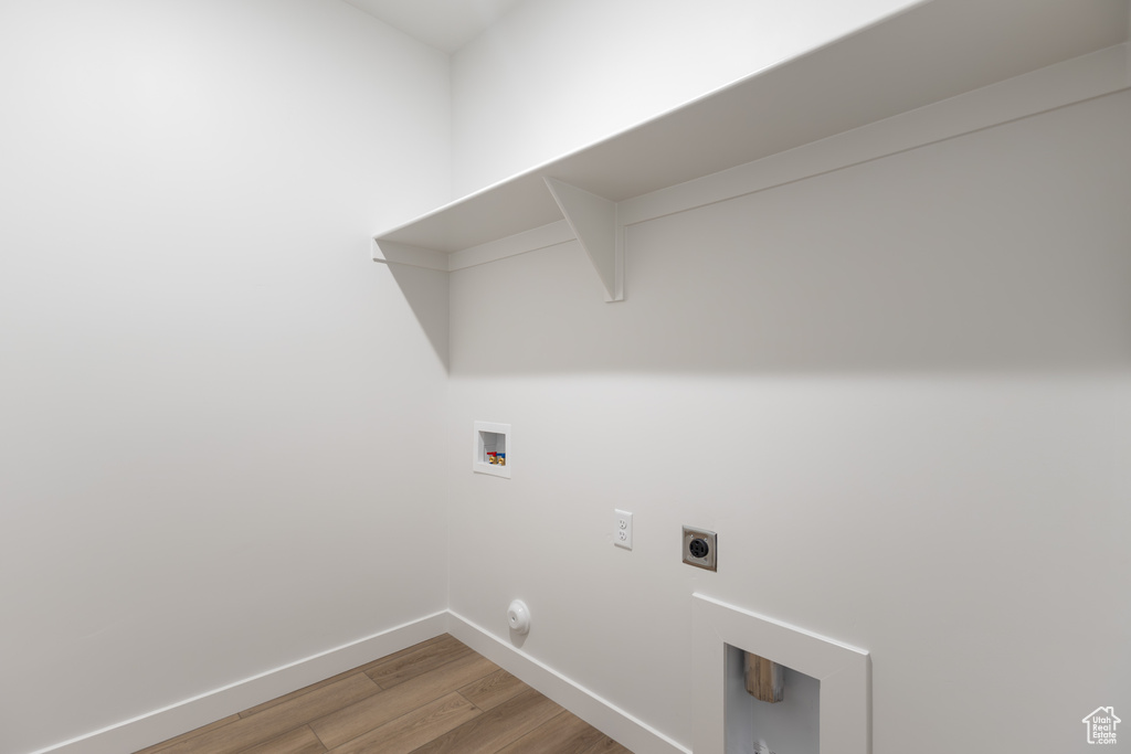 Washroom featuring light wood-style floors, hookup for a washing machine, baseboards, electric dryer hookup, and hookup for a gas dryer