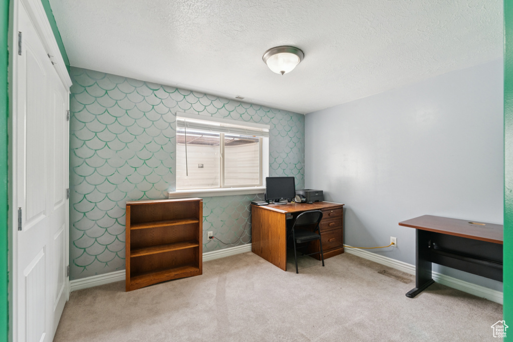 Home office with wallpapered walls, baseboards, a textured ceiling, and carpet