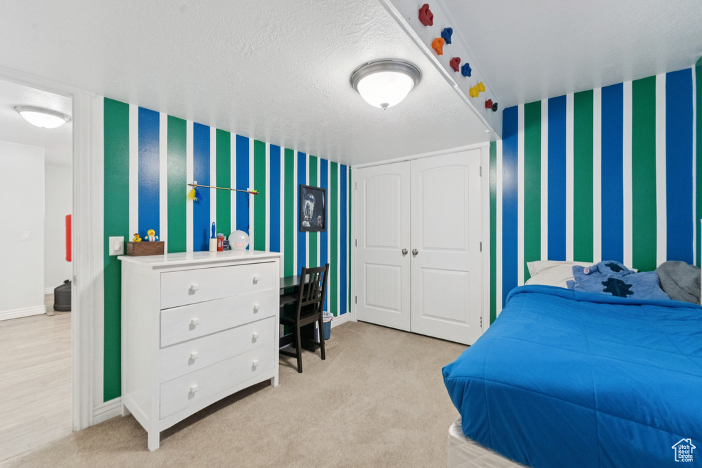 Carpeted bedroom featuring wallpapered walls, a closet, and baseboards
