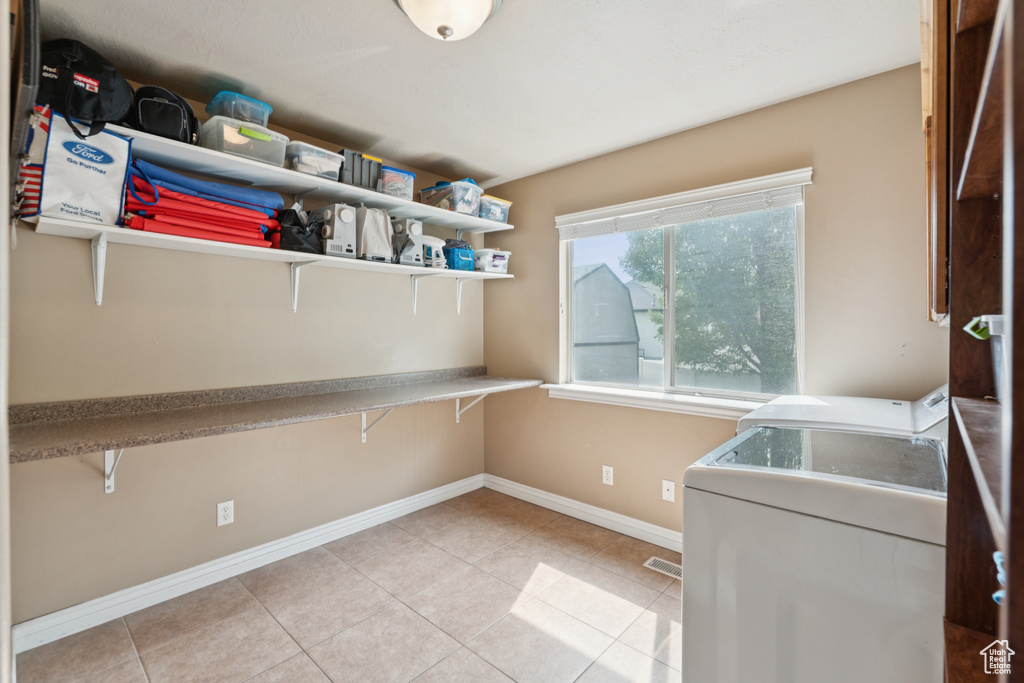 Laundry area featuring baseboards, light tile patterned floors, and separate washer and dryer