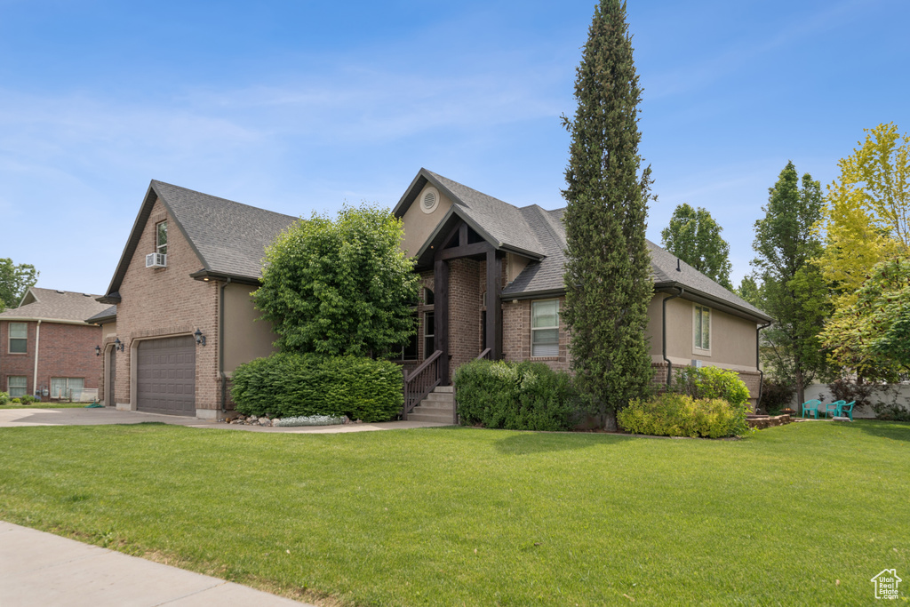 View of front of home featuring driveway, brick siding, a garage, and a front lawn