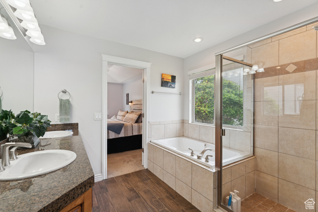 Ensuite bathroom featuring double vanity, wood finished floors, a stall shower, a garden tub, and recessed lighting
