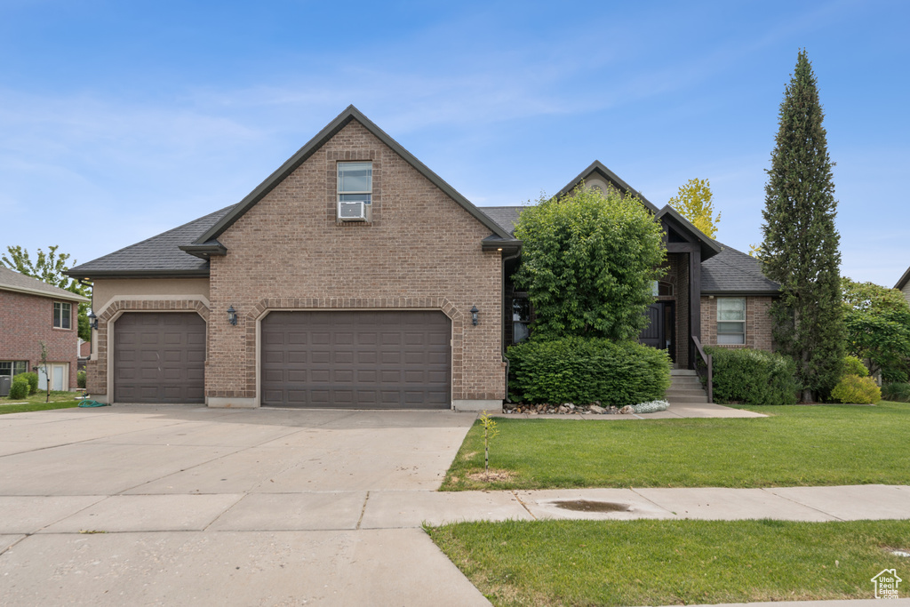 View of front facade with brick siding, driveway, and a front yard
