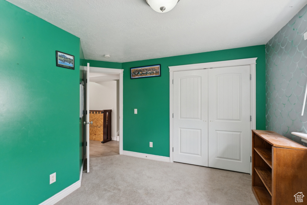 Unfurnished bedroom featuring a closet, carpet floors, and baseboards