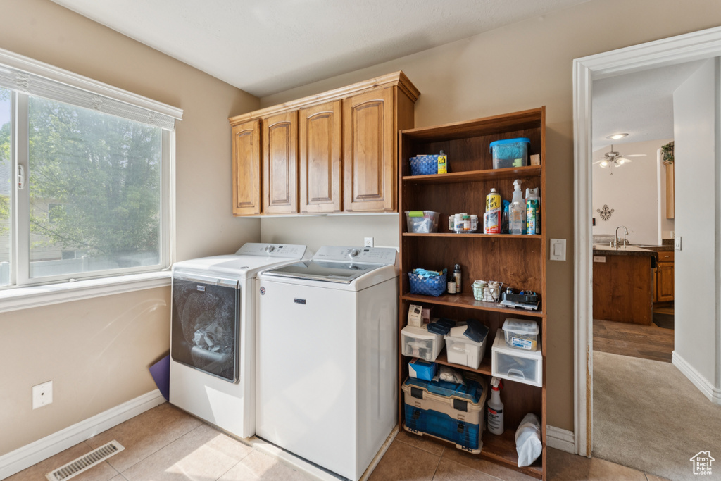 Laundry area featuring washing machine and dryer, cabinet space, baseboards, a ceiling fan, and light tile patterned flooring