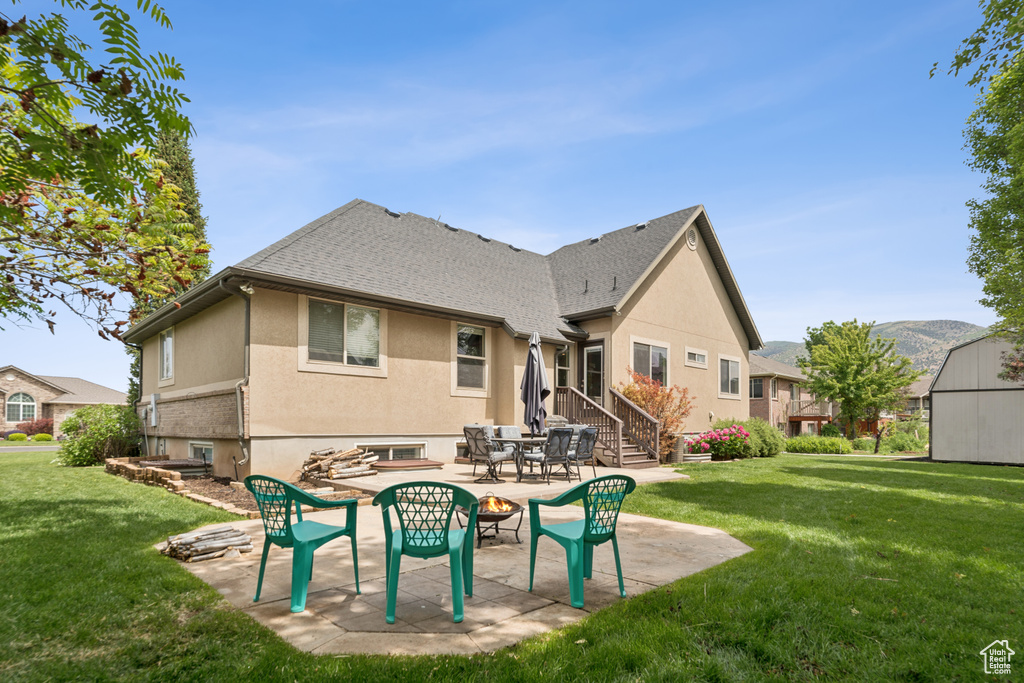 Rear view of property with a lawn, stucco siding, and a patio area