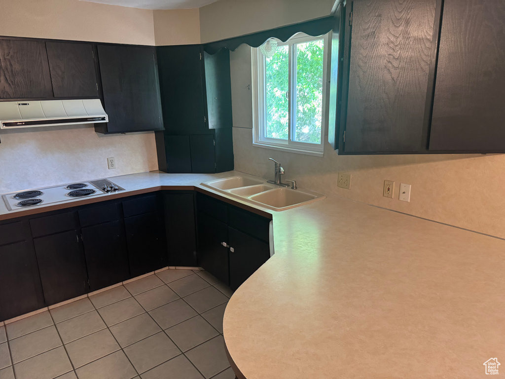 Kitchen featuring white electric cooktop, ventilation hood, a sink, light countertops, and light tile patterned flooring
