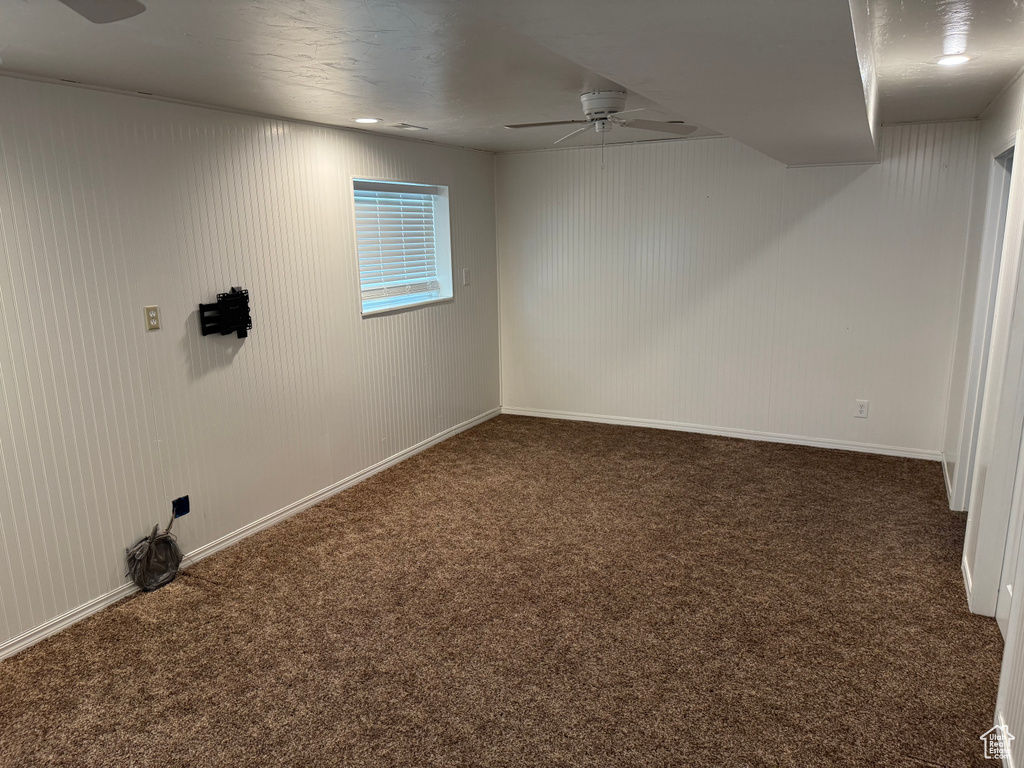 Basement featuring a ceiling fan, carpet, and baseboards
