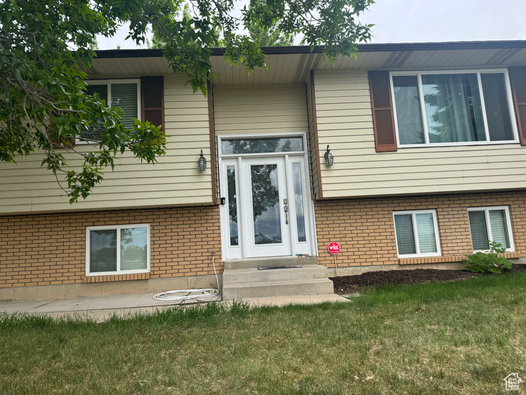 Doorway to property with a lawn and brick siding