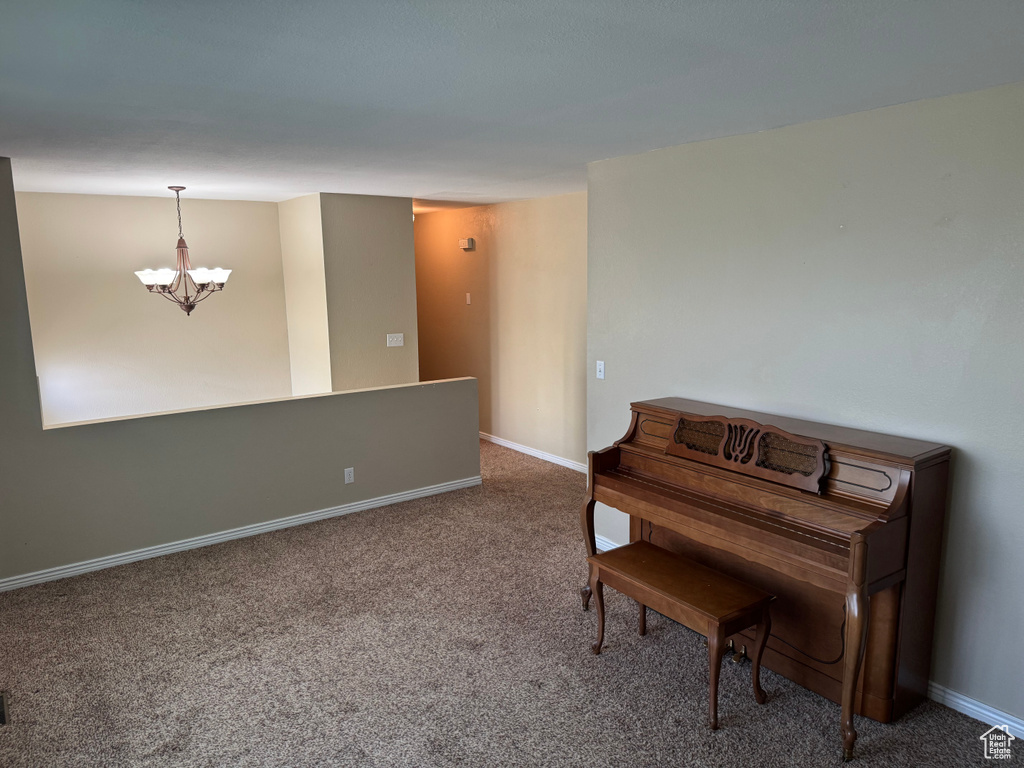 Sitting room with a chandelier, carpet, and baseboards