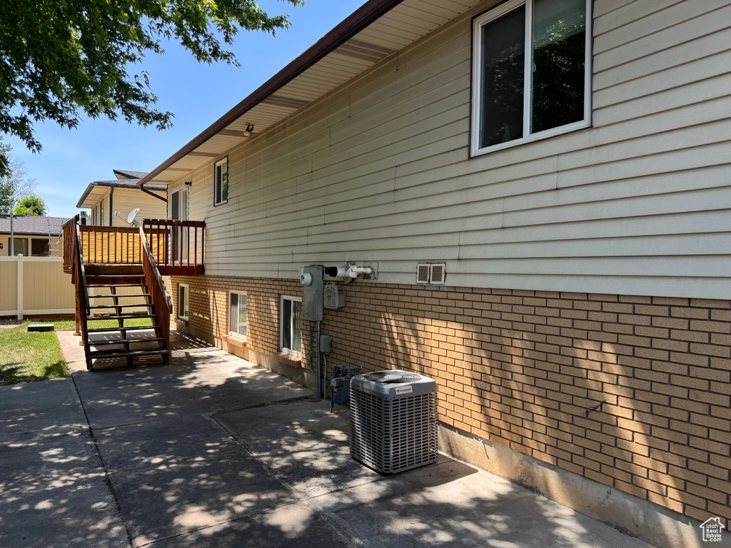 View of property exterior with cooling unit, stairway, a patio, a deck, and brick siding