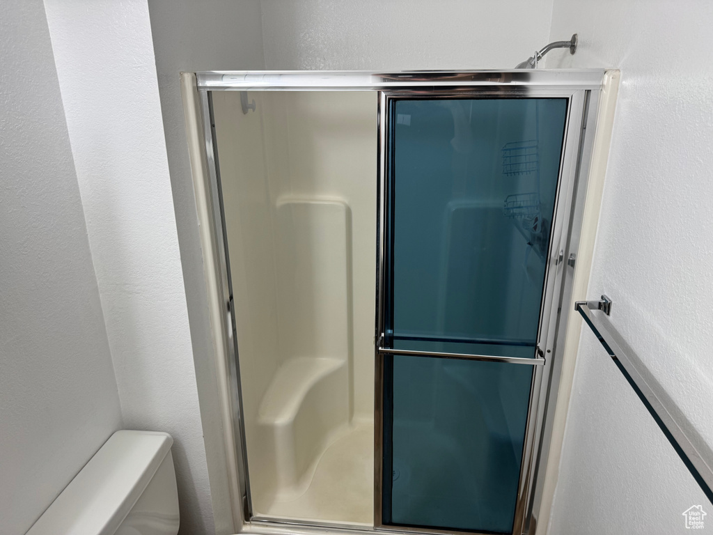 Bathroom featuring a shower stall, toilet, and a textured wall