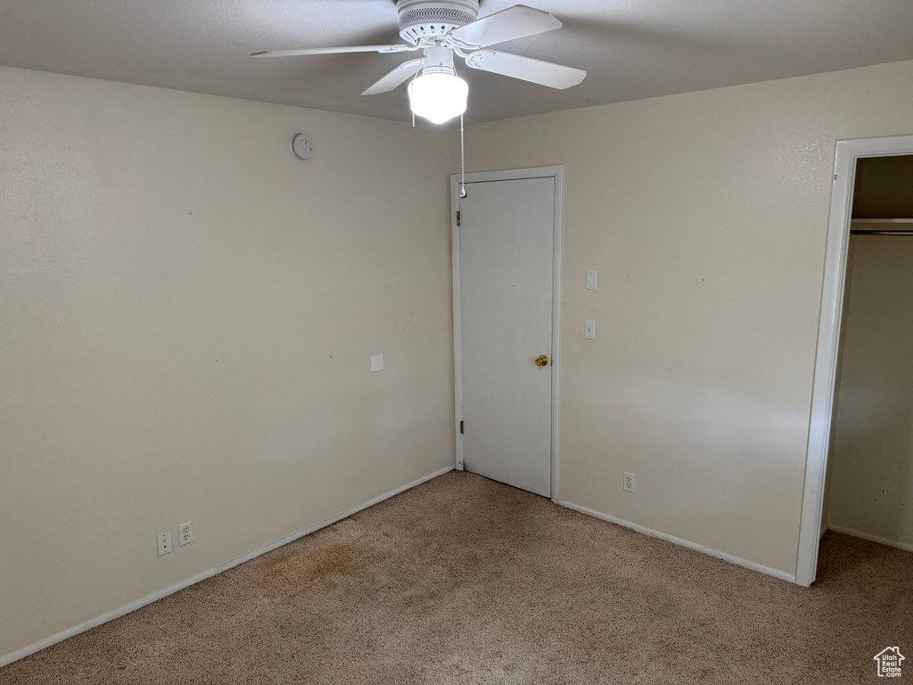 Unfurnished bedroom with carpet flooring, a closet, baseboards, and a ceiling fan