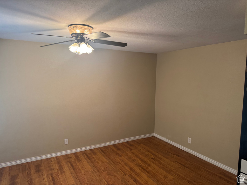Unfurnished room featuring a ceiling fan, dark wood finished floors, and baseboards