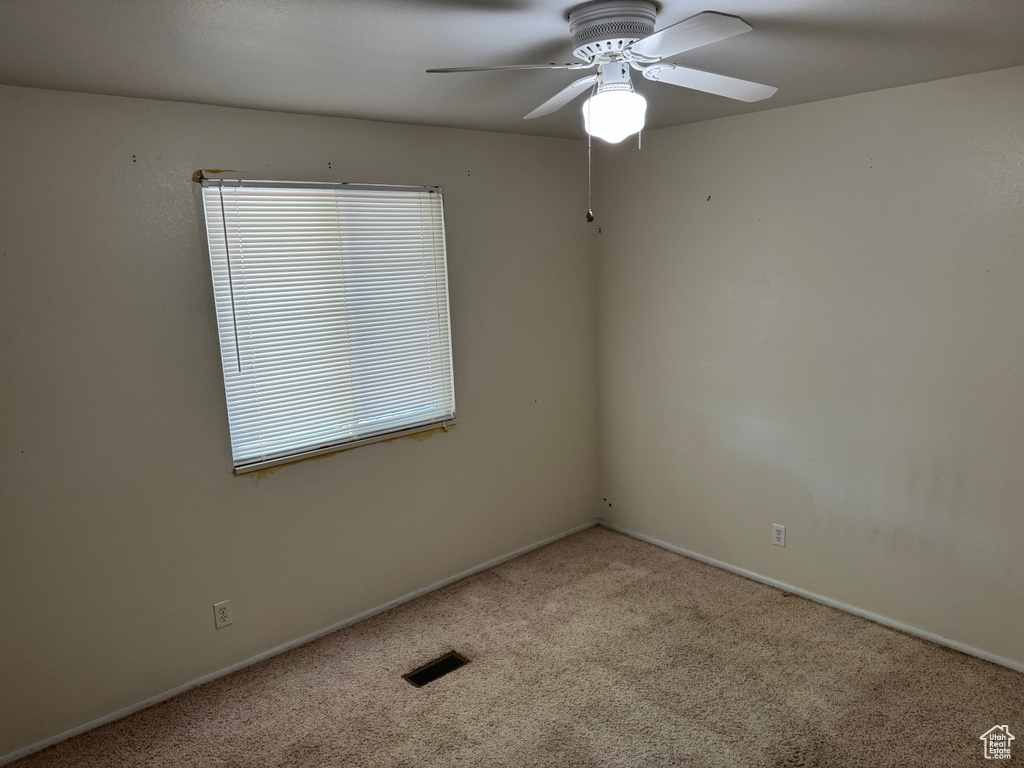 Carpeted empty room with a ceiling fan and baseboards