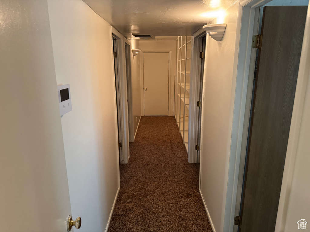 Hall with dark colored carpet and baseboards