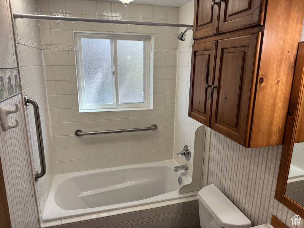 Bathroom featuring tiled shower / bath combo and toilet