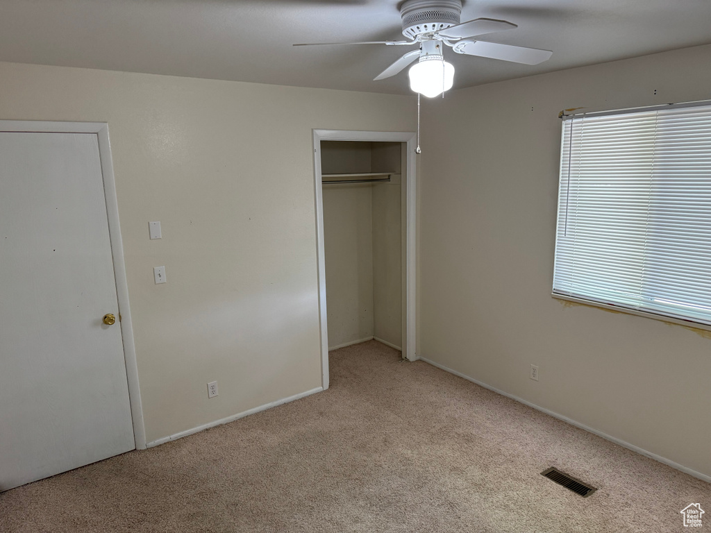Unfurnished bedroom with light colored carpet, a closet, a ceiling fan, and baseboards