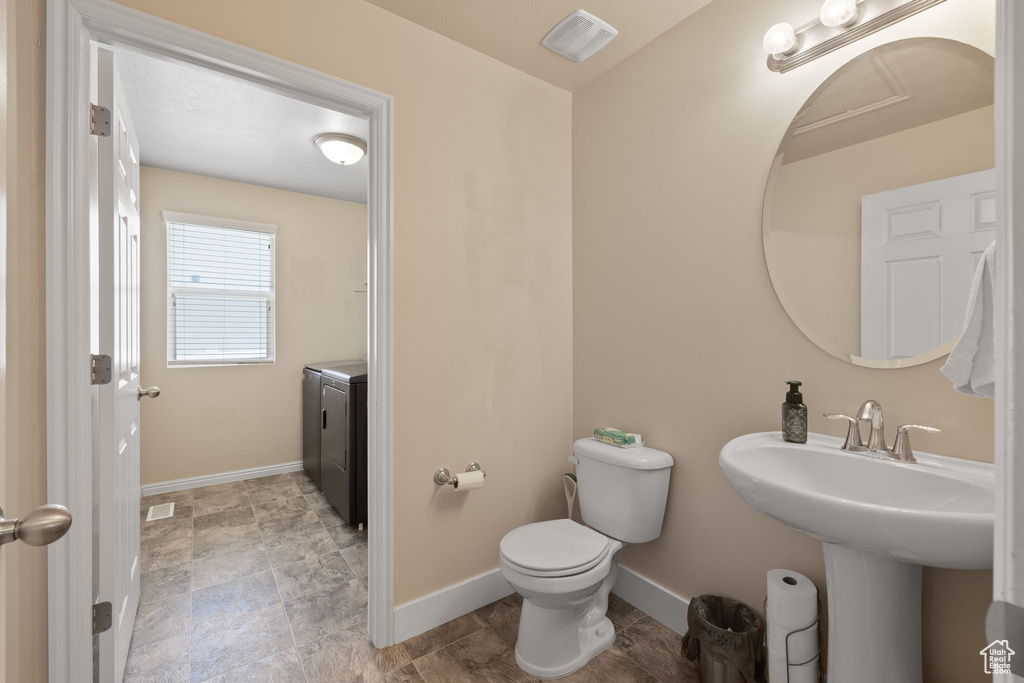 Bathroom featuring baseboards, toilet, and washer and dryer