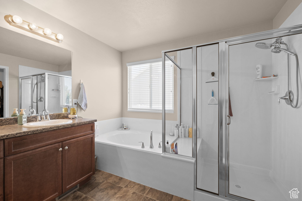 Bathroom featuring a shower stall, vanity, and a garden tub