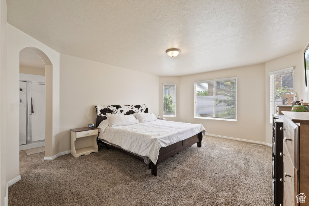 Bedroom with carpet floors, arched walkways, and baseboards
