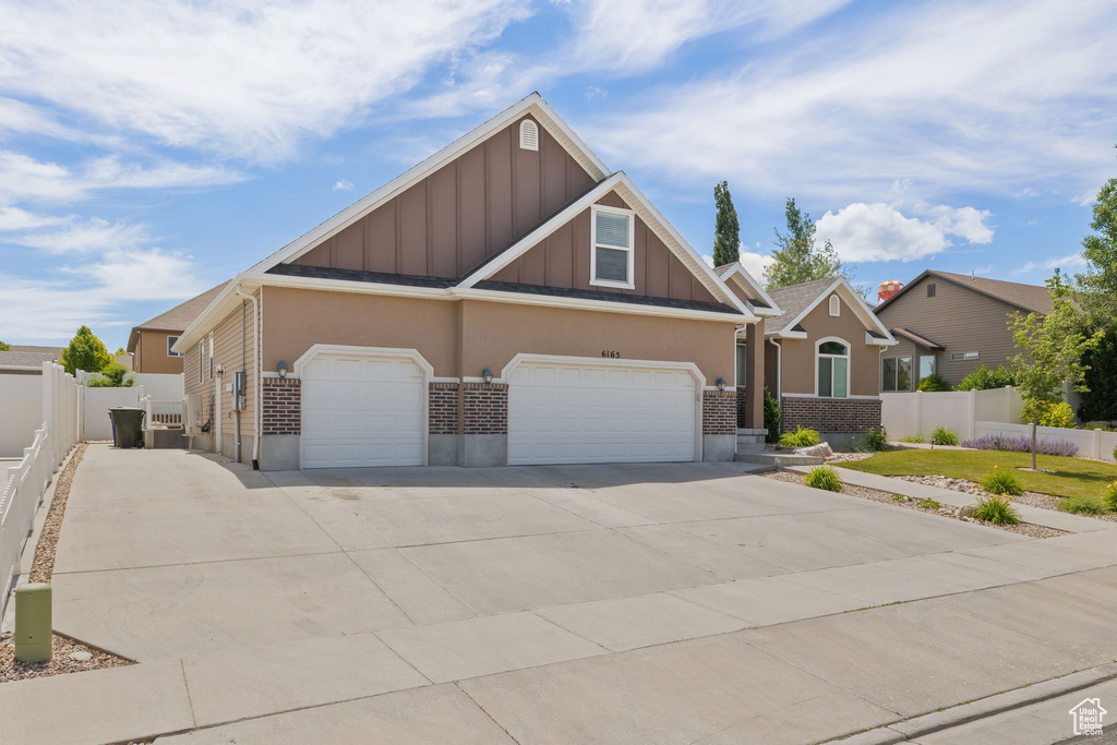 Craftsman-style home with board and batten siding, concrete driveway, brick siding, and an attached garage