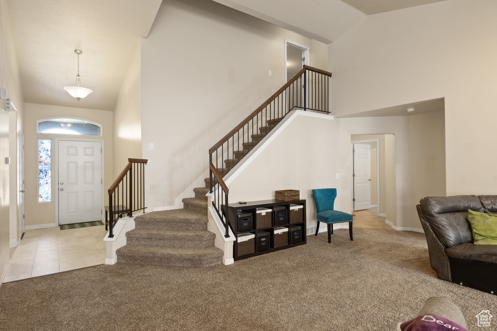 Carpeted entryway featuring high vaulted ceiling, stairs, and baseboards