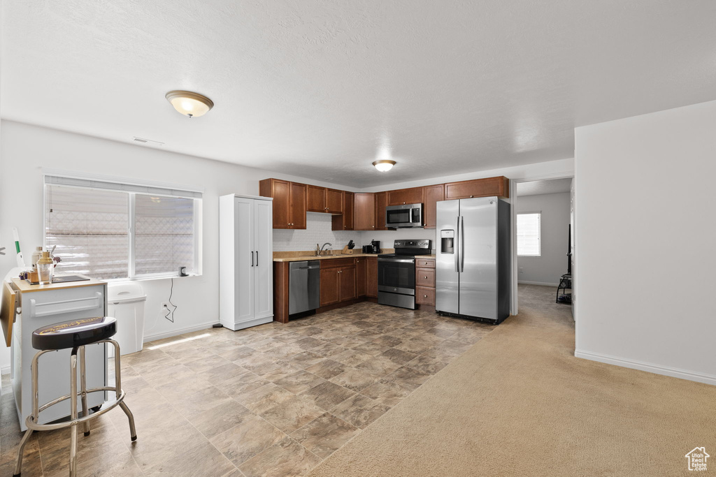 Kitchen featuring appliances with stainless steel finishes, a sink, baseboards, and light countertops