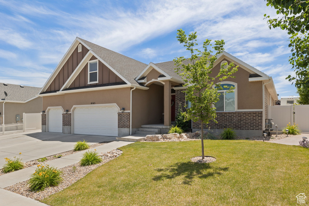 View of front of home with concrete driveway, board and batten siding, brick siding, a gate, and an attached garage
