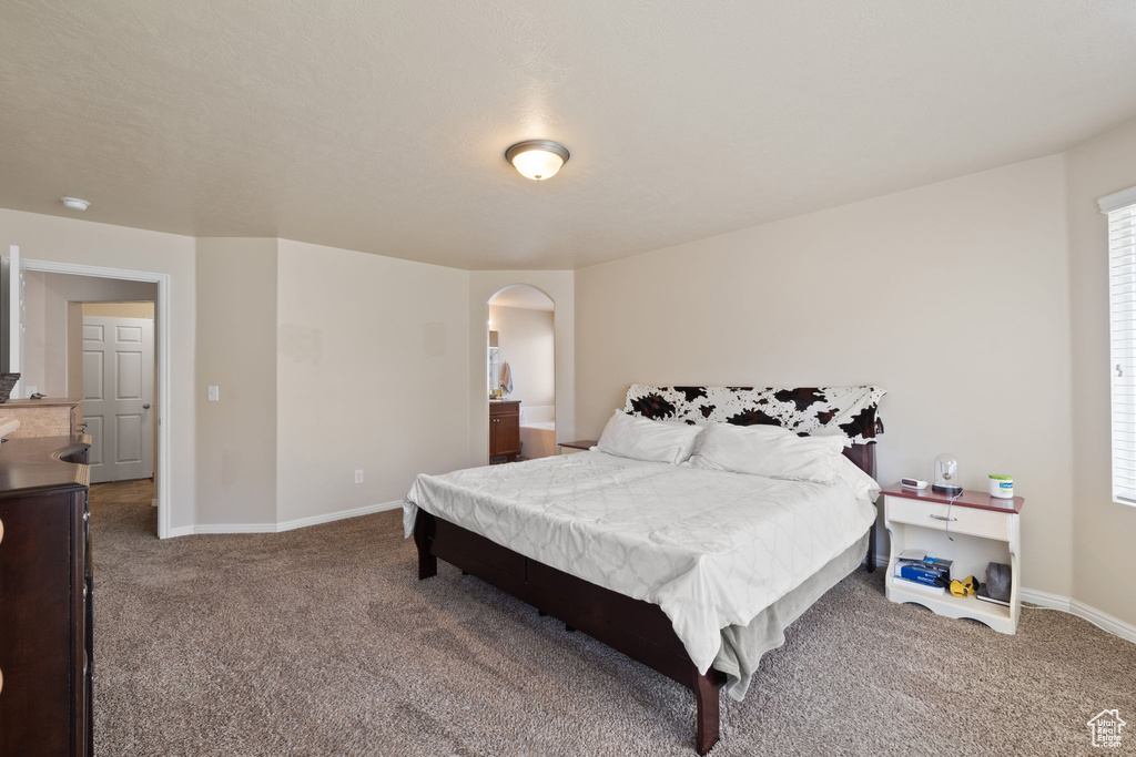 Carpeted bedroom with arched walkways and baseboards
