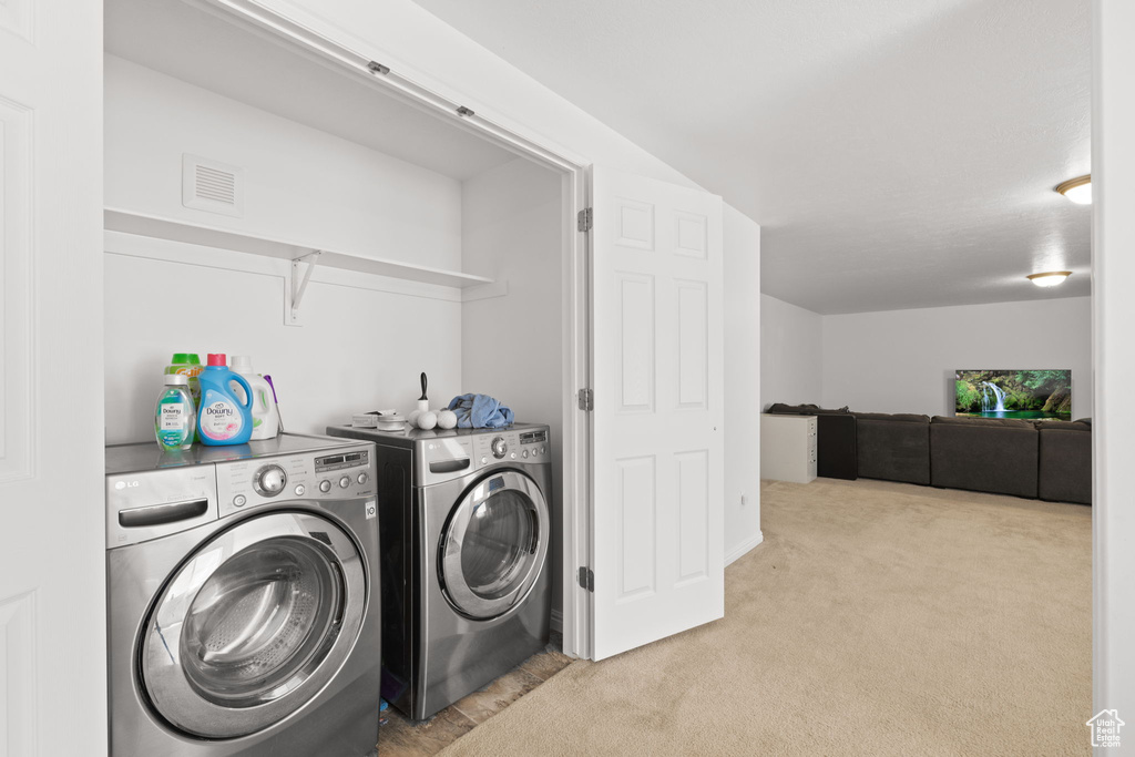 Laundry area featuring separate washer and dryer and light carpet