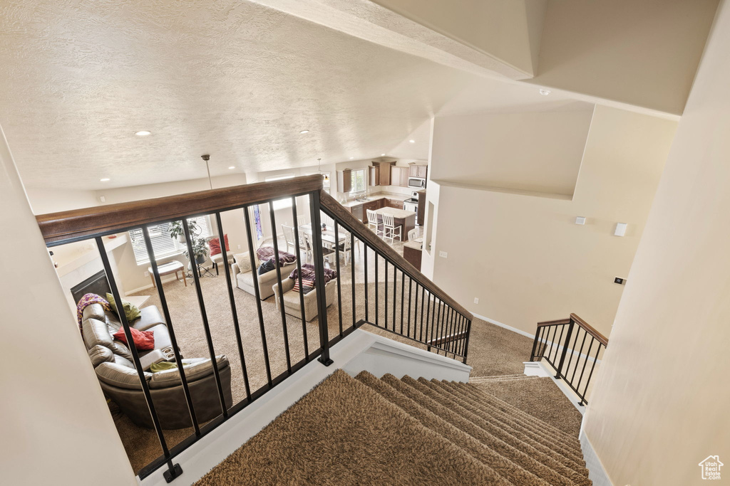 Staircase featuring carpet floors, a textured ceiling, baseboards, and recessed lighting