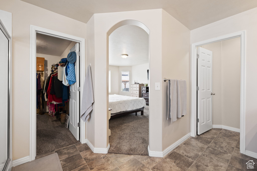 Hall featuring arched walkways, baseboards, and carpet flooring