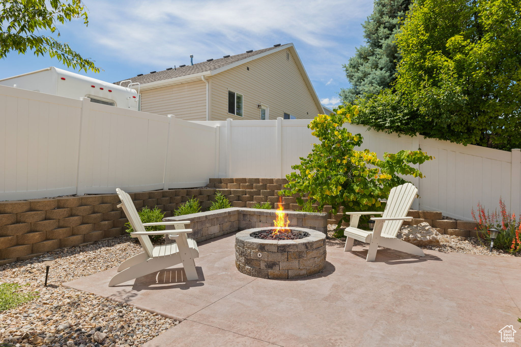 Fenced backyard featuring a fire pit and a patio
